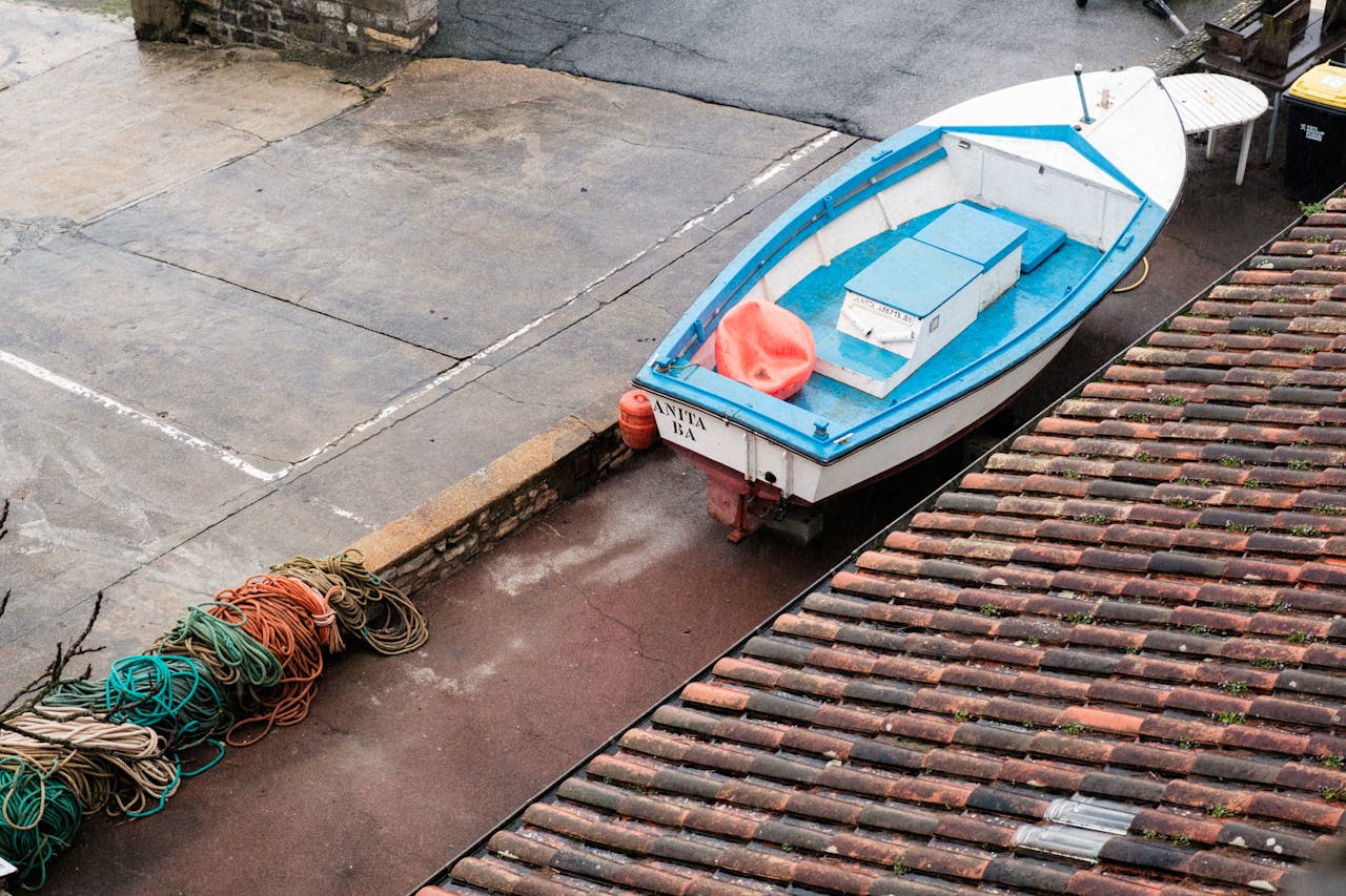 A vibrant small boat docked in an empty harbor with neatly coiled ropes.