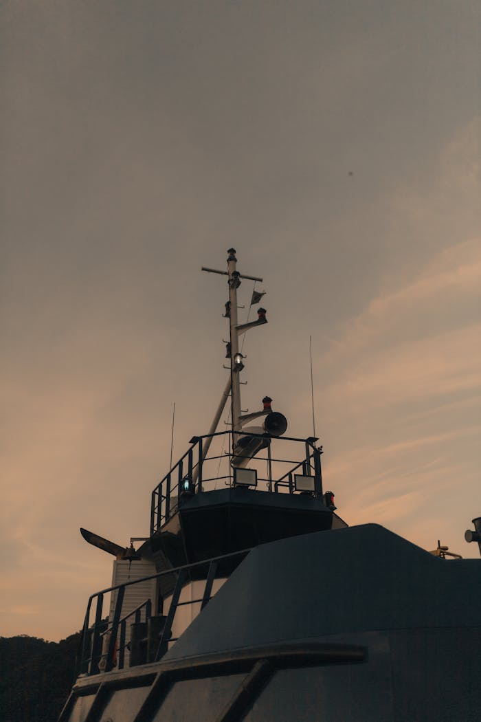 A boat silhouette with antenna mast set against a warm sunset sky, capturing a serene nautical scene.